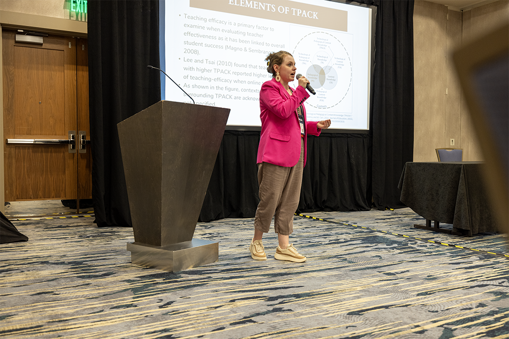 Dr. Kenna Vowell speaking in front of a podium and screen